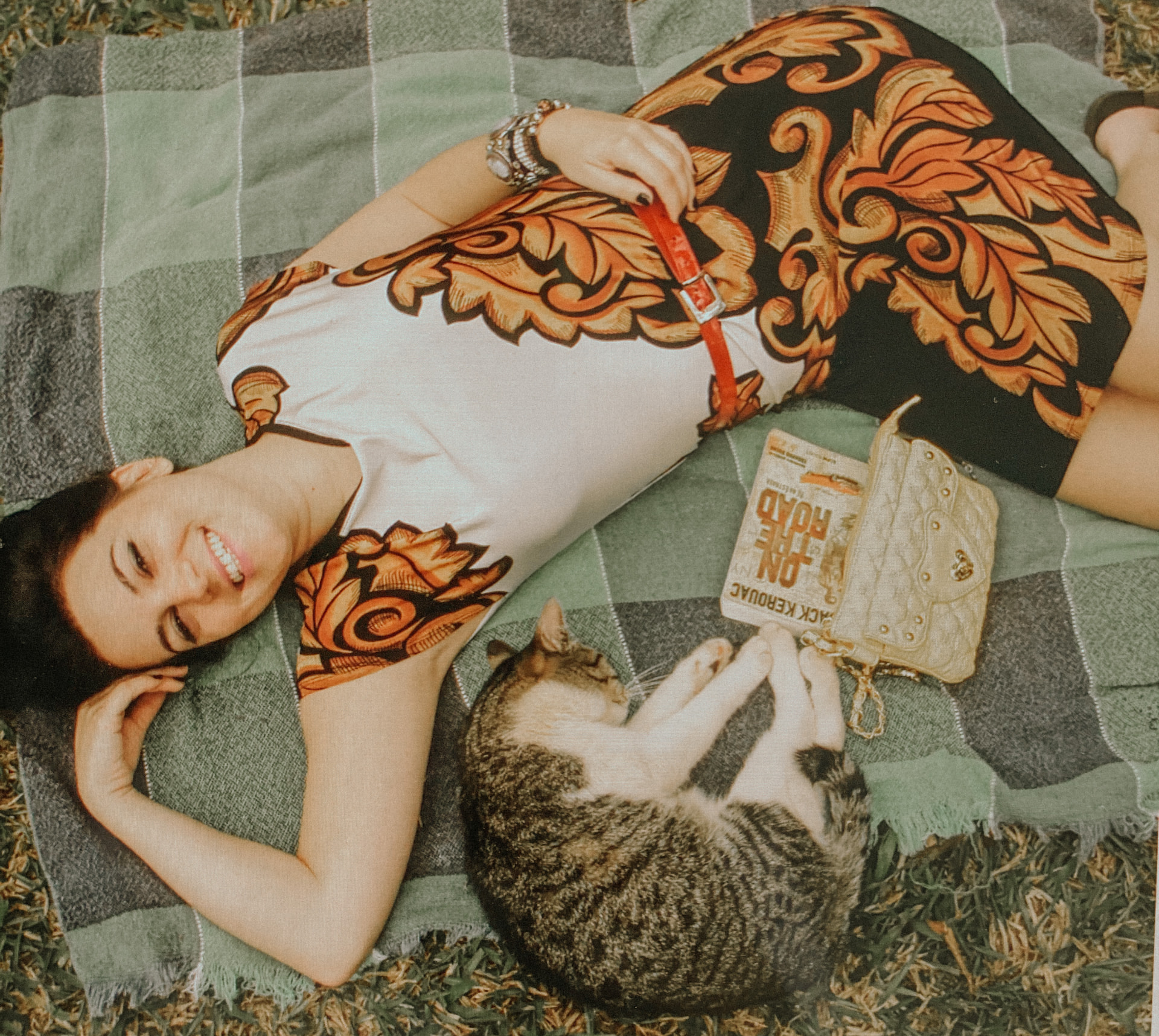 Luana deitada numa manta com um gato e um livro