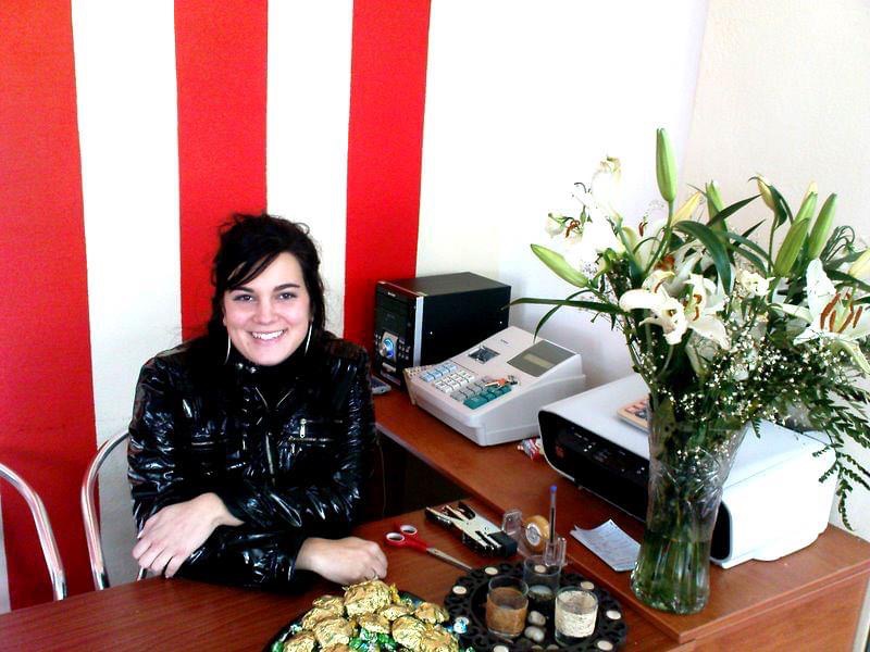 Luana sorrindo atrás do balcão de uma loja